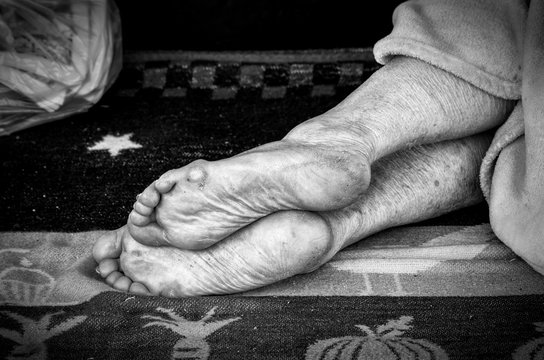 Barefooted homeless or refugee person sleeping on the street with dirty feet skin - Powered by Adobe