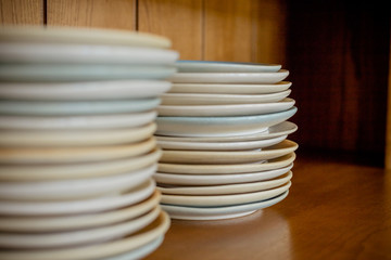 Group of white plates stacked together.Clean plates isolated on wooden shelf.Selective focus. Copy space