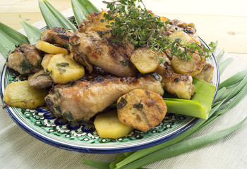Fried chicken drumsticks with potatoes, rosemary and herbs.