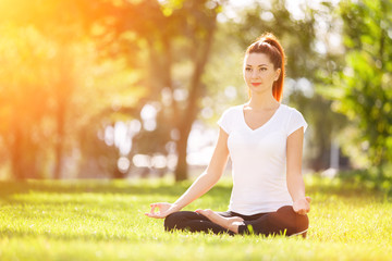 Yoga outdoor. Happy woman doing yoga exercises, meditate in the park. Yoga meditation in nature....