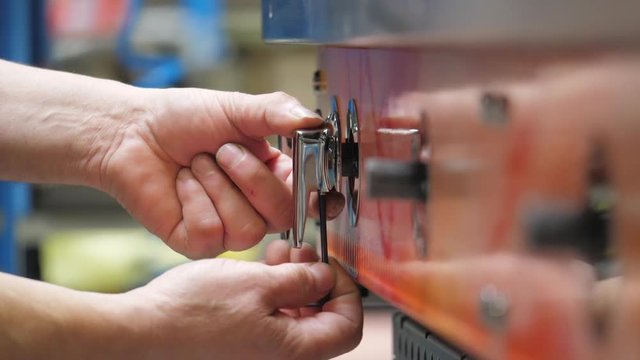 Close up, worker installs knobs on oven in oven factory