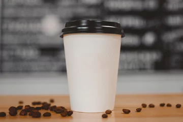 Des tasses de café en papier blanc avec des bouchons noirs présentés dans les grains avant se trouvent sur la table. Concept de livraison de nourriture