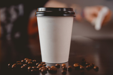 Des tasses de café en papier blanc avec des bouchons noirs présentés dans les grains avant se trouvent sur la table. Concept de livraison de nourriture