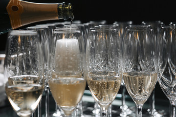Pouring sparkling wine from bottle into the champagne glass.