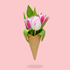 Ice cream cone with tulip flowers on pink background. Minimal spring concept. Flat lay.