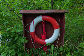 red white life preserver green grass water summer nature bridge reflected in water