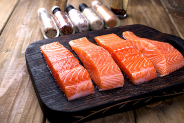 Fillet of salmon on the board. Preparation of a delicious and healthy dinner. Dietary food and spices. Wooden background. place for text