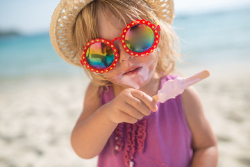 Little girl with hat and sunglasses eatin ice cream