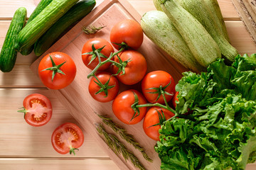 Close-up of fresh, ripe tomatoes with vegetables on wooden background. Top view.
