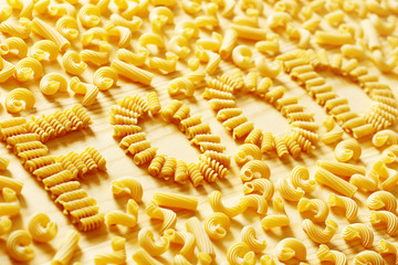 Yellow pasta on a wood background and word food