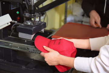 Young woman printing on cap at workshop