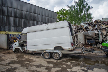 A small machine pulls a large car for scrap