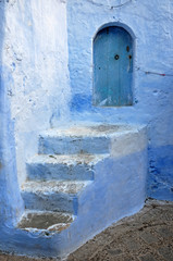 Stairs to a wooden door in the ancient city of Chefchaouen. Morocco.