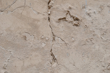 old chipped plaster on the concrete wall, beige texture, background