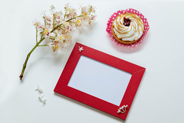 branch of the blossoming chestnut, red frame for a congratulation inscription, lemon cake  on a white background. Top view