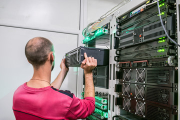 Technical Support Engineer performs the installation of a new server in a rack with computer...
