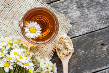 Obraz na płótnie Canvas cup of herbal chamomile tea with fresh daisy flowers on wooden background. doctor treatment and prevention of immune concept, medicine - folk, alternative, complementary, traditional medicine 