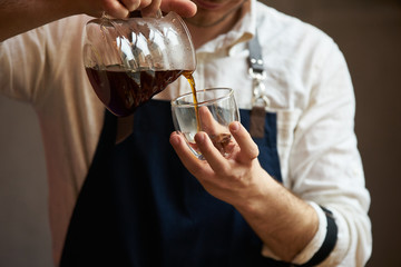 Barista pouring hot coffee into a cup, close-up