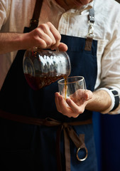 Barista pouring hot coffee into a cup, close-up