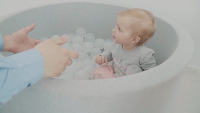 Beautiful little girl play with her father in pool with balls. Slow-motion