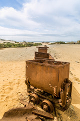 Old and rusty mine carts in the open air on the sand in Sardinia