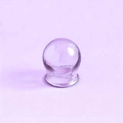 Medical cupping glass on pastel lilac background