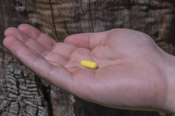  Capsule in hand on the background of wood