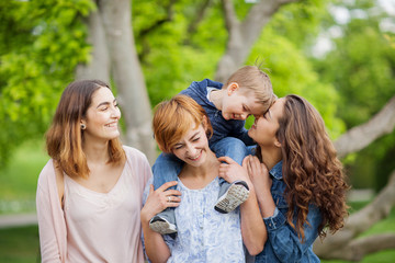 Happy young family enjoying free time in the park, mother, sisters and brother - 205141426