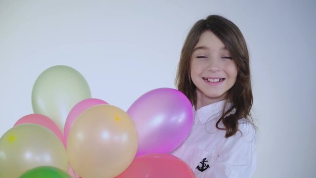 Surprised young girl catches balloons and looks at camera on background