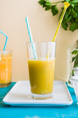 healthy Apple , lemon  and celery juice on a white plate over a blue board and against a yellow pale background.
