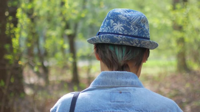 Young woman in hat walking in the tree forest
