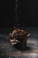 tasty chocolate cupcake with glaze and sugar spreading on table