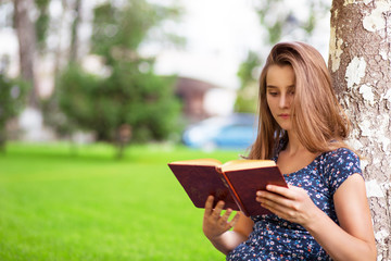 woman studying reading a book while sitting in campus