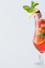close up view of summer strawberry cocktail with ice, mint, lemon and orange pieces isolated on white