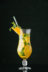 close up view of summer fresh cocktail with straw, mint, lemon and orange pieces isolated on black