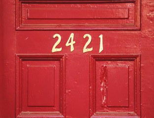 Red wooden door with gold numbers