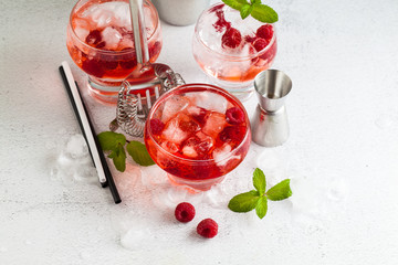 summer alcoholic drink with raspberry liqueur, ice and leaves of fresh mint on the table. bar accessories.