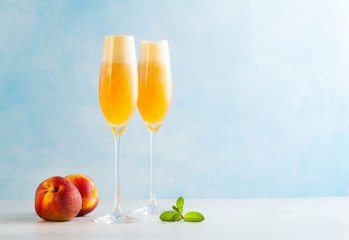 two glasses of champagne with a cocktail of Bellini and fresh peaches on a blue background. summer refreshing drink