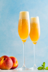 two glasses of champagne with a cocktail of Bellini and fresh peaches on a blue background. summer refreshing drink