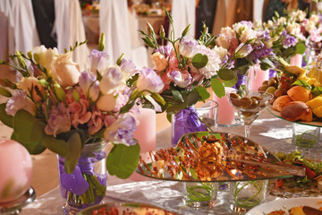 wedding decoration bouquets of pink and white flowers near the candles on the table in restaurant