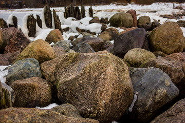 Jetty Pillars and Rocks Covered witn Snow in a Cloudy Winter Day