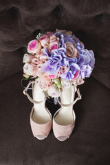 Nude beige wedding shoes on a brown armchair. Bridal bouquet