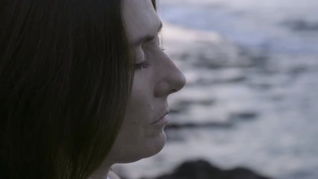 Close up of mindful woman with closed eyes listening to ocean and meditating