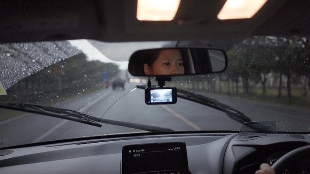 Slow motion, Asian women Drive along the road on a rainy day.