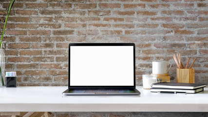 Contemporary workspace with blank screen laptop on white wood table.