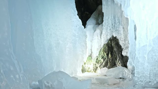 Hacker hacks the server. Man to program on laptop in ice cave. Around the mysterious ice grotto. Man hides himself in a hood. Hacker has criminal cases on the Internet. Guy is warming himself with the