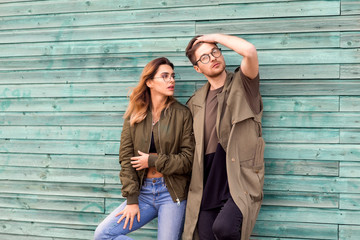 fashion couple standing posing near green wooden wall