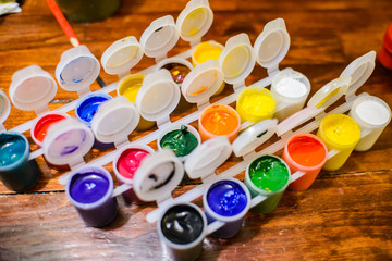 Multicolored gouache paints on a wooden background