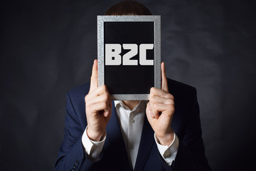 In the hands of a businessman a frame with the inscription:B2C