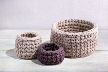 Fototapeta na wymiar Knitted baskets on a wooden table. Handmade crochrting background.